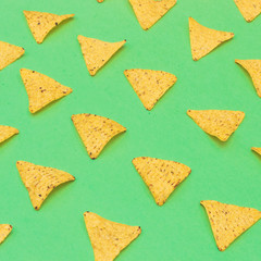 Nachos chips laid out on a green background. Fashion food in minimal.