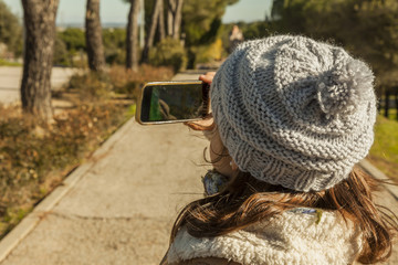 Rear view little girl taking pictures with a smartphone in the p