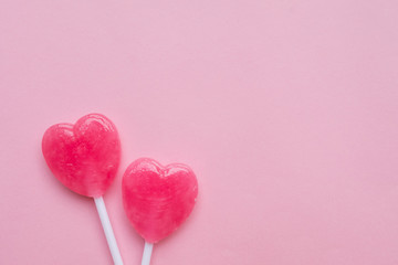 two Pink Valentine's day heart shape lollipop candy on empty pastel pink paper background. Love...