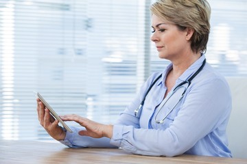 Doctor sitting at desk and using digital tablet