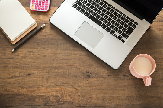 Working desk, Office and home office concept. with Laptop, Pencil, Memo, Calculator and Milk cup on wooden table.