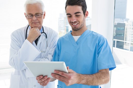 Surgeon and doctor discussing over digital tablet