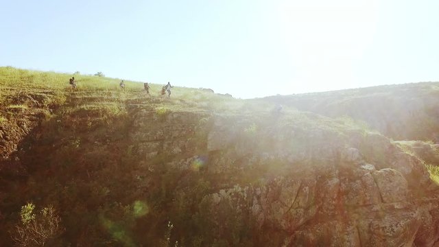 Tourists joyfully running towards each other near rocky cliff in prairie in slowmotion. Flyover drone shot