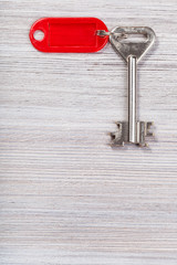 big key with red key chain on wooden surface