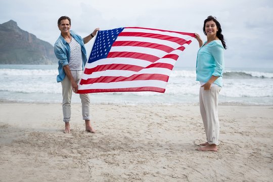 Portrait of couple holding american flag on beach