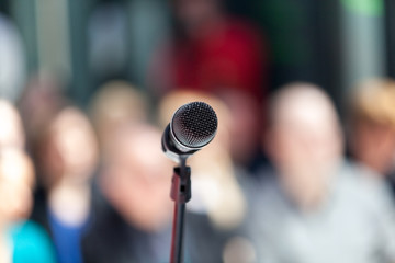 Microphone in focus, blurred audience in background