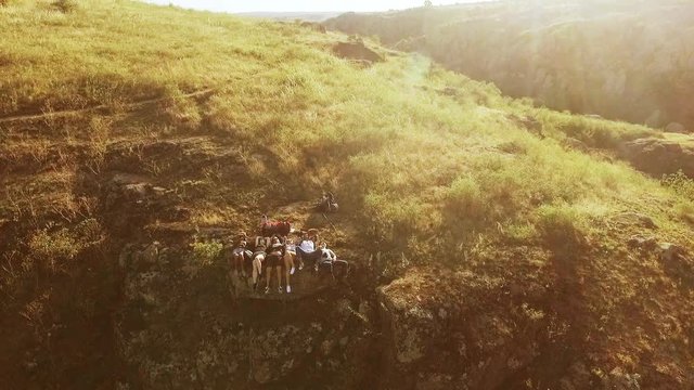 Group of torurists lying on backs under sun and rejoicing in slowmotion. View with tilt from drone