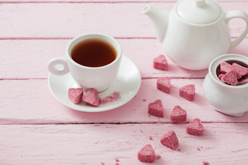 Granulated pink sugar  in the shape of heart and cup of tea  on