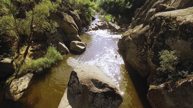Caucasian male jumping into river from huge boulder in slowmotion. Panoramic drone shot
