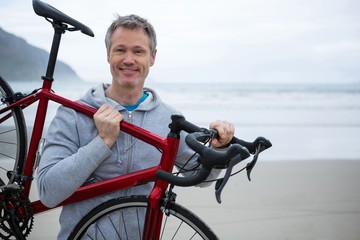 Man carrying bicycle on beach