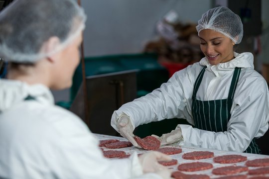 Female butchers processing hamburger patty