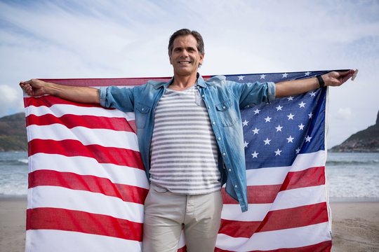Man holding American flag on beach