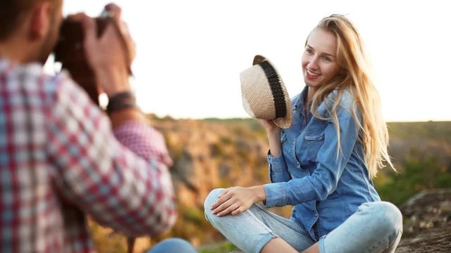 Close up view of posing young female in jeans shirt and pants while her boyfriend photos her with film camera in slowmotion