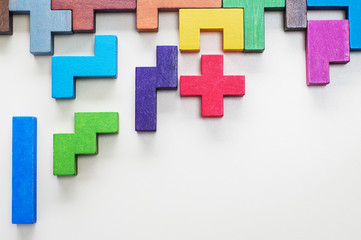 Different colorful shapes wooden blocks on beige background, flat lay. Geometric shapes in different colors, top view. Concept of creative, logical thinking or problem solving. Copy space.