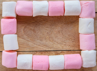 frame of marshmallows with empty place for text on  wooden background - top view