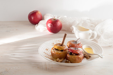 Baked apples stuffed with walnuts and honey on white plate