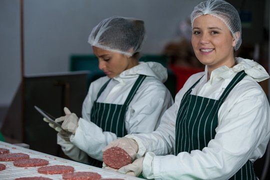 Female butchers maintaining records over digital tablet