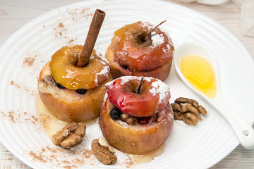 Baked apples stuffed with walnuts and honey on white plate