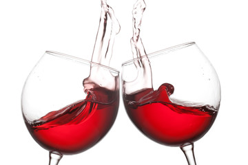 Two red wine glasses and splashing flow on white background. Celebration party concept photo. Macro...