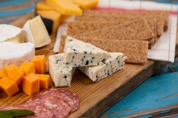 Cheese with ham and crispy biscuits on chopping board