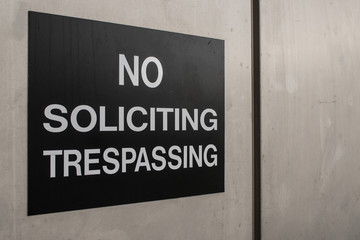 No Soliciting and No Trespassing sign on a metal surface