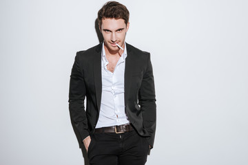 Attractive young businessman posing at studio holding cigarette.