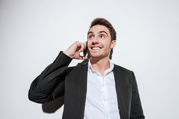 Happy businessman posing at studio talking by phone.