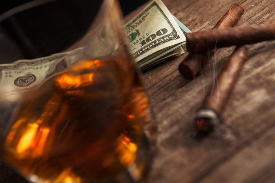 Money with glass with brandy and smoking cigarette