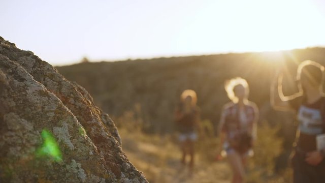 Three tourists stopping near big rock to look down at map to find right direction. Close up in slowmotion