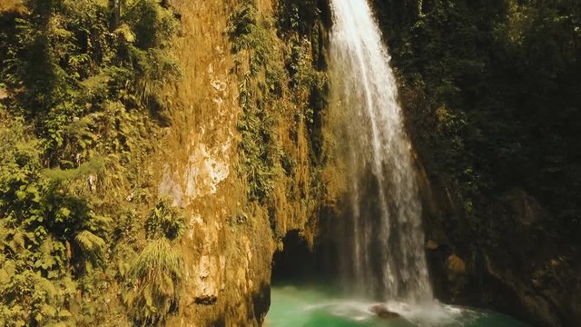 Beautiful waterfall in green forest in jungle. Aerial view:tropical rain forest with waterfall.Waterfall with natural swimming pool in a mountain river canyon. Philippines, Cebu. 4K video. Travel