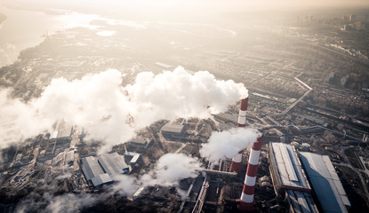 Air pollution by smoke coming out of two factory chimneys. Industrial zone in the city. Kiev, Ukraine, aerial view