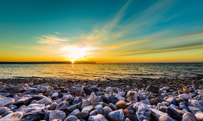 Stones on a beach with sunset on the ocean sea.