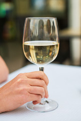 Woman sitting at table with white glass of wine.