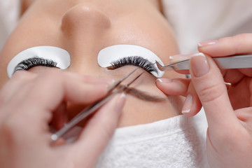Obraz na płótnie Canvas Stylist lengthening lashes for female in a beauty salon.