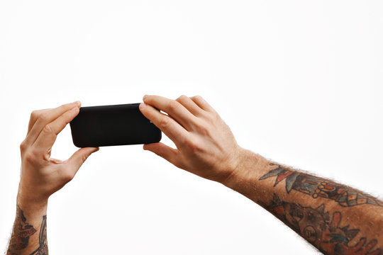Two slightly unfocused men's tattooed arms shows a video on a smartphone on foreground, isolated on white, mockup image