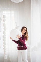 A girl in a cherry sweater sits posing in white decorations