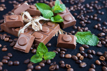 Chocolate, coffee grains and mint on a dark background closeup