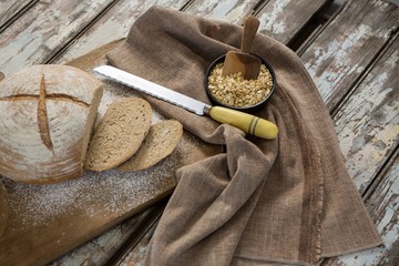 Bread loaf with knife and bowl of oats
