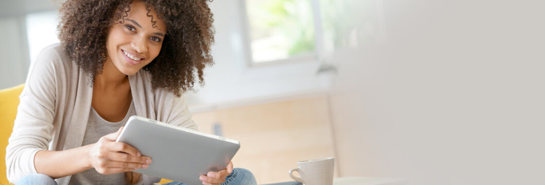 Mixed-race woman websurfing on digital tablet at home