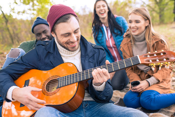 Friends enjoying guitar in autumn park