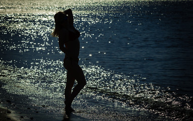 Silhouette of a girl standing on  sea shore.