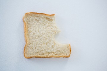 Bread slice with broken edge on white background