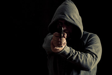 Thug in hoodie points gun