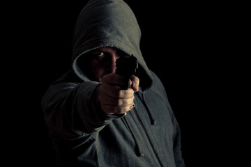 Thug in hoodie points gun