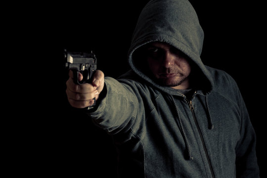 Thug in hoodie points gun