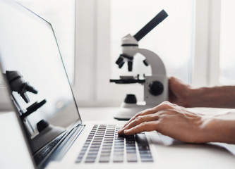 Scientist or student using  laptop computer and microscope