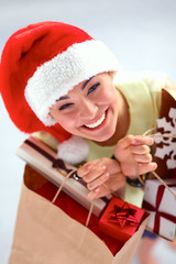 Smiling woman in santa hat with many gift boxes on white background