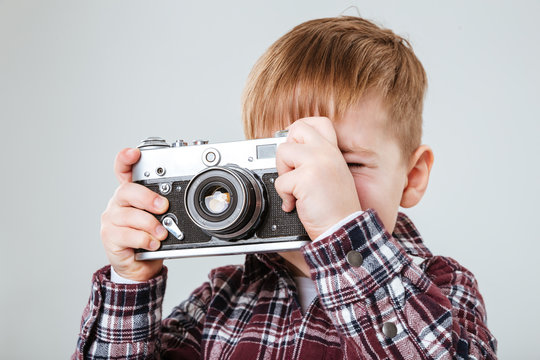 Little boy taking pictures with old vintage photo camera