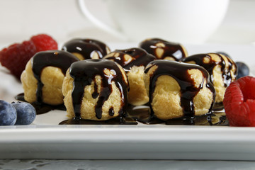 Delicious profiteroles with cream and chocolate glaze on a plate