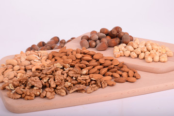 Different nuts served on a wooden board on white background